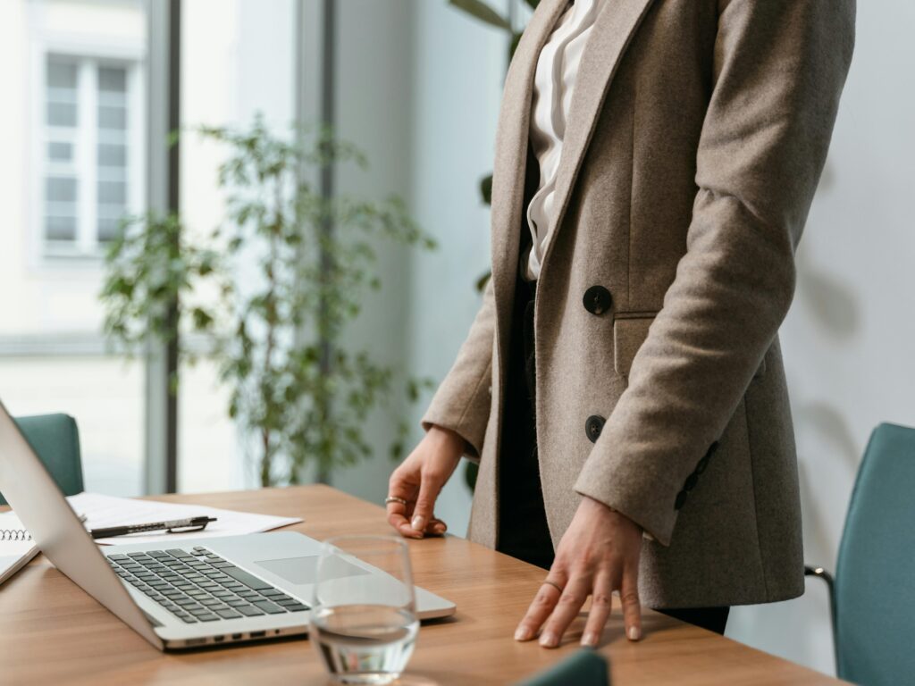A professional businesswoman in a stylish office environment with a laptop and notes.